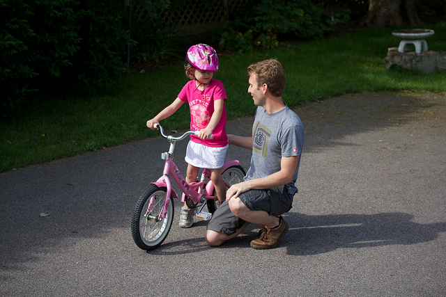 Padre animando a su hija antes de que comience a andar sola en bicicleta